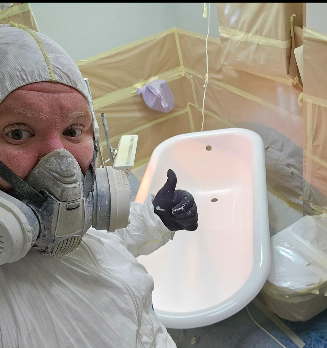 photo of glossy baths re-enamelling owner Seamus with a thumbs up, in ppe, in a room full of masking up and a completed bath in Newport